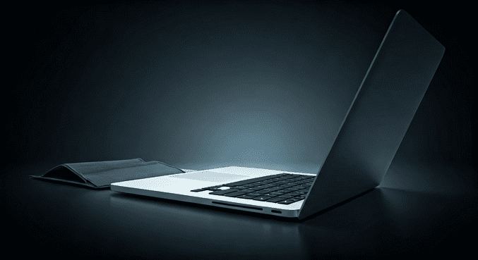 alt_text: Osoba starannie pakuje laptopa w etui, dbając o jego bezpieczeństwo podczas podróży.